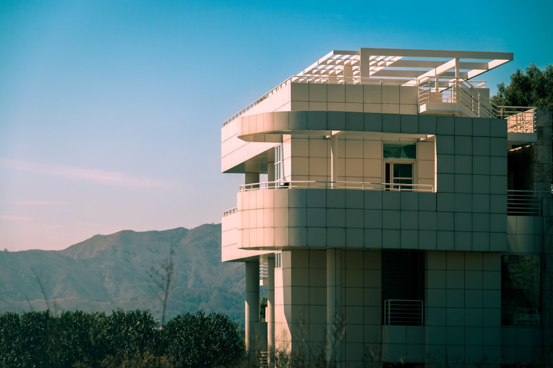 A modern building stands against a mountain backdrop.