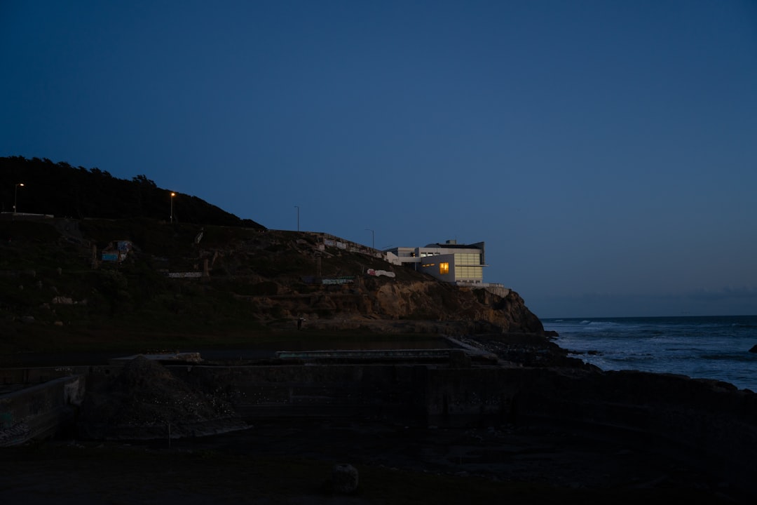 a house sitting on top of a cliff next to the ocean
